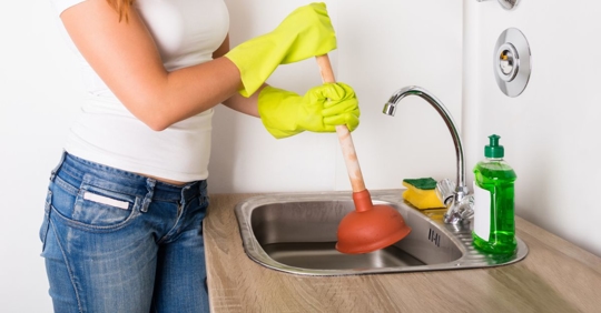 Homeowner using plunger in a clogged sink