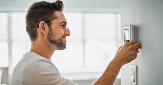 Man adjusting thermostat settings
